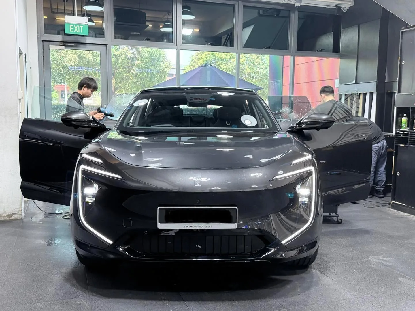A black Avatr 07 being tinted indoors with technicians working on both sides, doors open.
