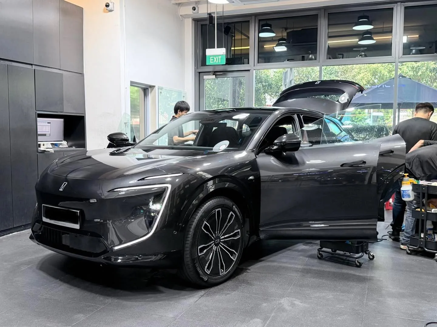 A black Avatr 07 with open driver door being worked on by technicians in the workshop.