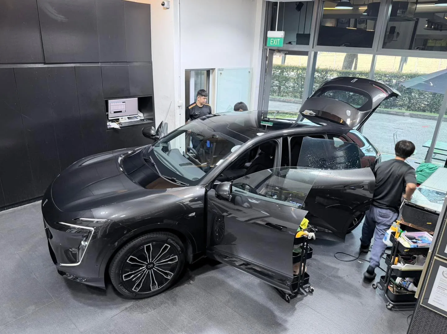 A black Avatr 07 with open doors during the tinting process, technicians visible inside the workshop.