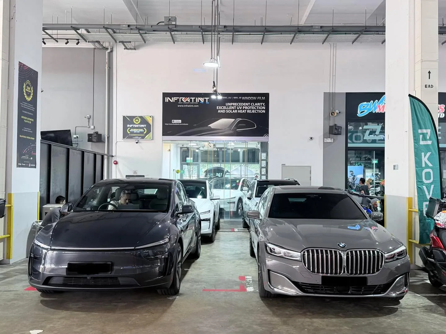 Black Tesla Model Y and grey BMW X3 SUV parked indoors.