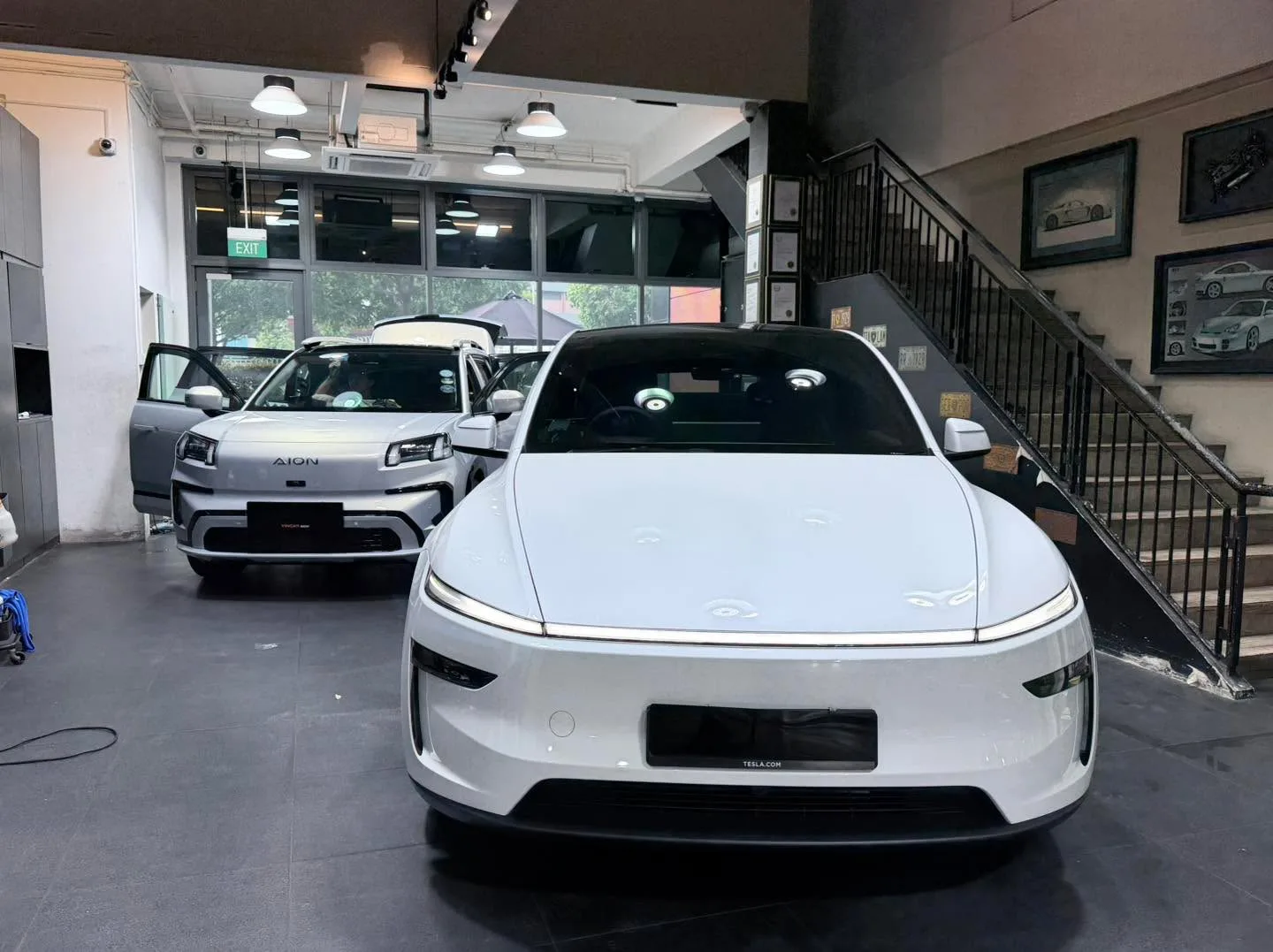 White Tesla Model 3 and white Lexus IS300H saloon parked indoors.