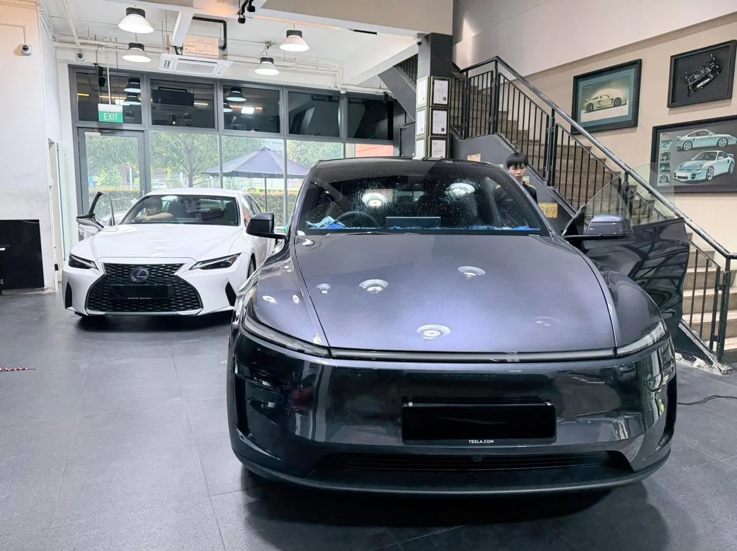 Black Tesla Model Y and white Lexus IS300H parked indoors.