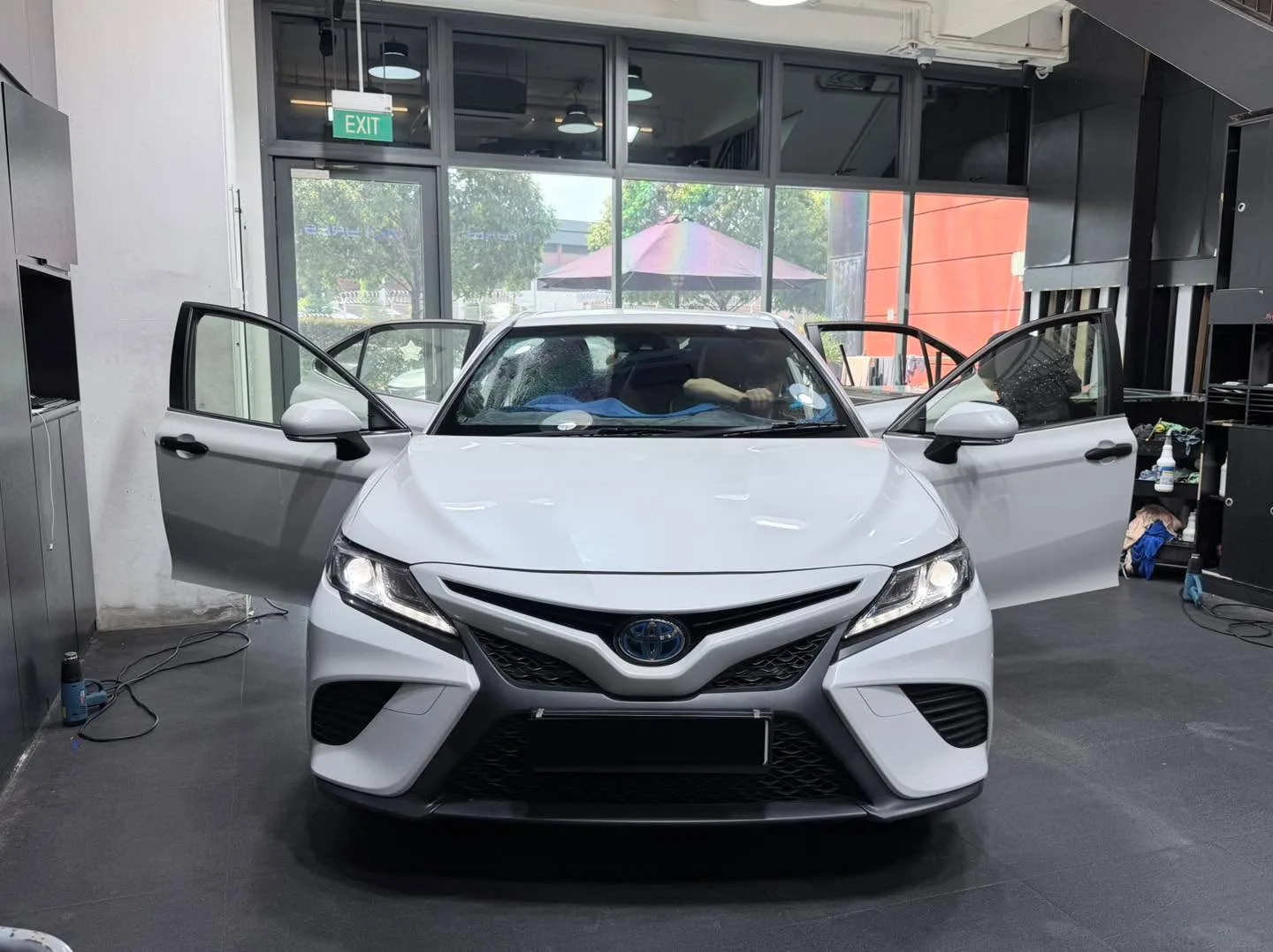 A white Hyundai Elantra coupe with doors open, facing the camera indoors.
