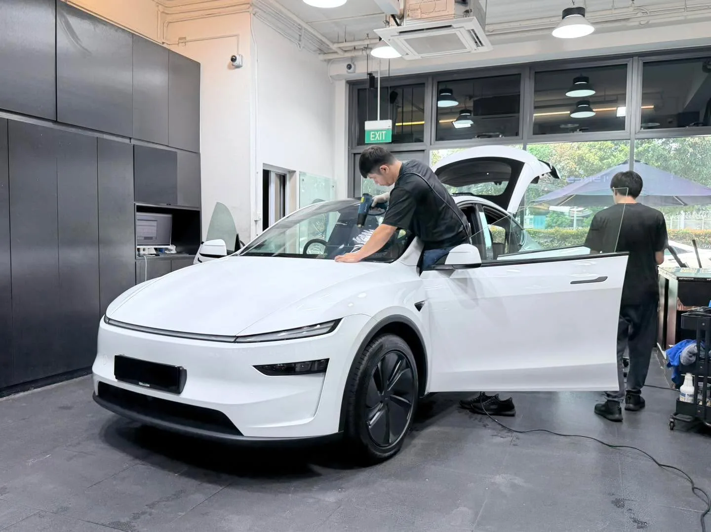 A white Tesla SUV with doors open during installation work.