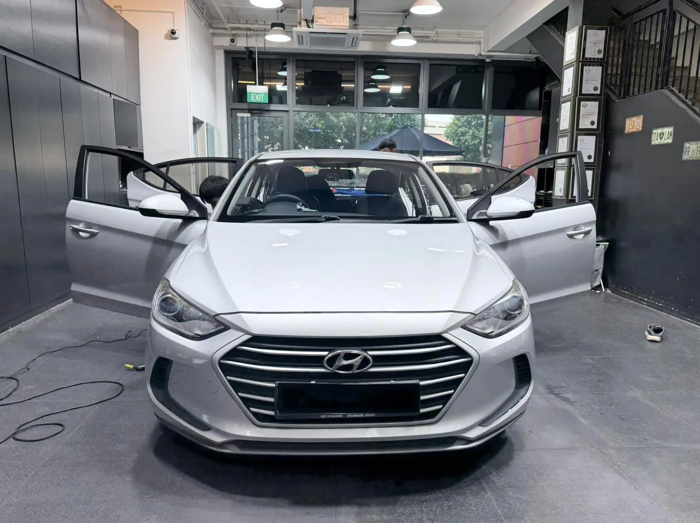 A white Hyundai Elantra with both doors open in the workshop.
