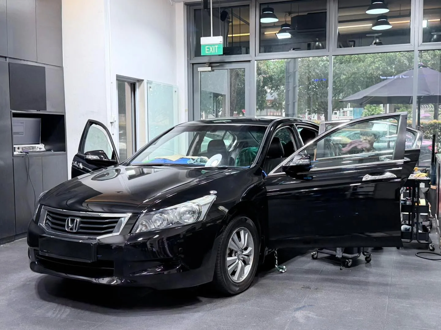 A black Honda Accord with doors open inside the workshop.