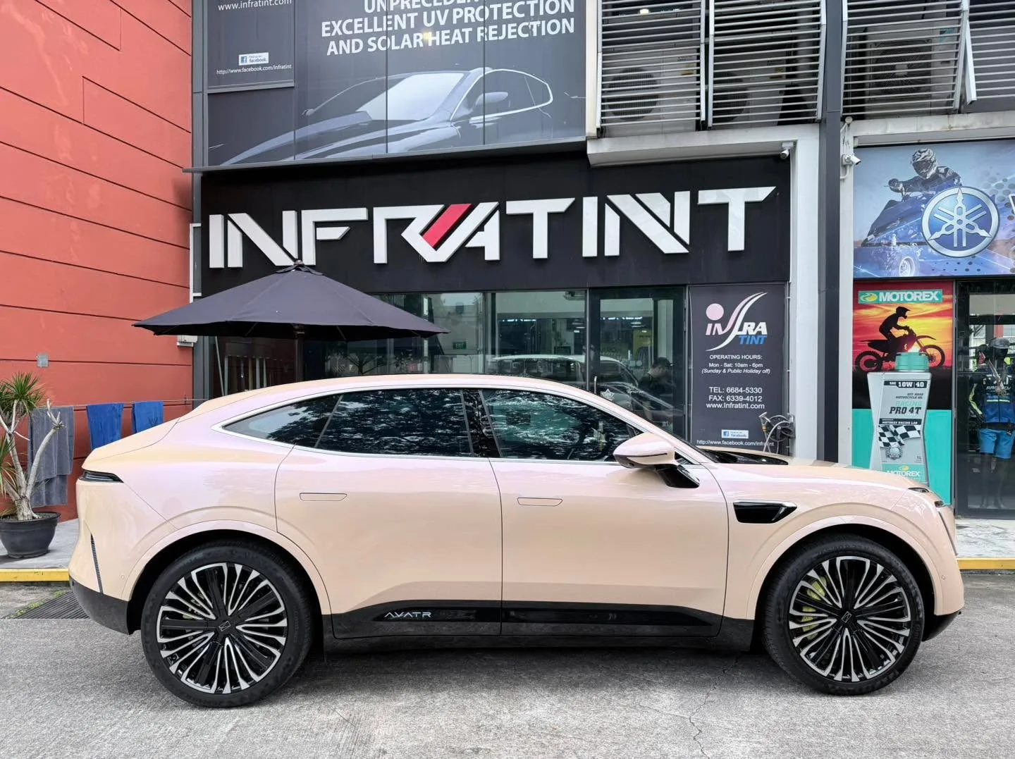 The same cream Avatr 11 SUV photographed from the side outside the Infratint shopfront, showing black-tinted windows along the body.