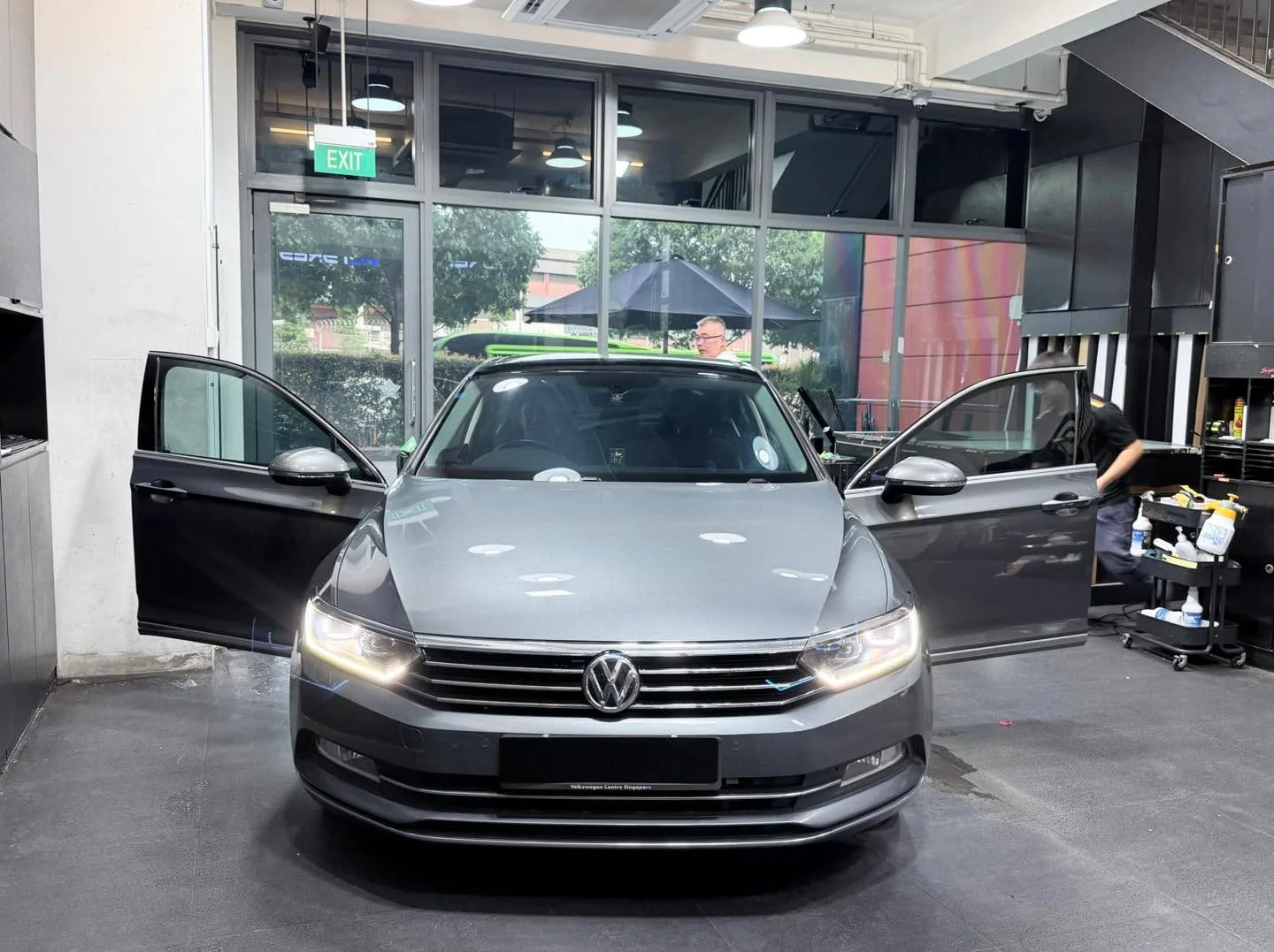 A silver saloon with Volkswagen grille visible, doors open in a workshop.