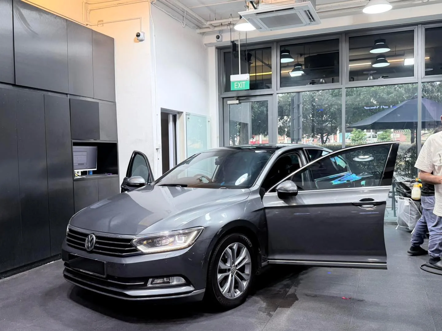 A grey saloon with Volkswagen badging and open door in the workshop.