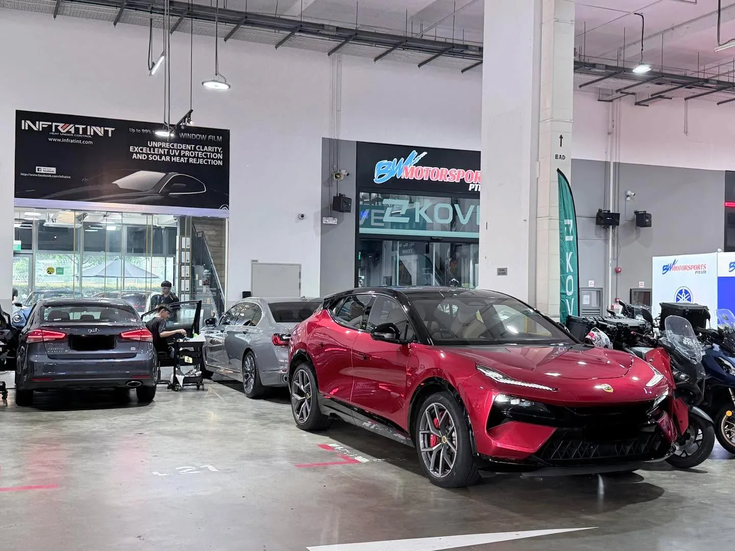 A red sports car and silver sedan parked indoors at the workshop.