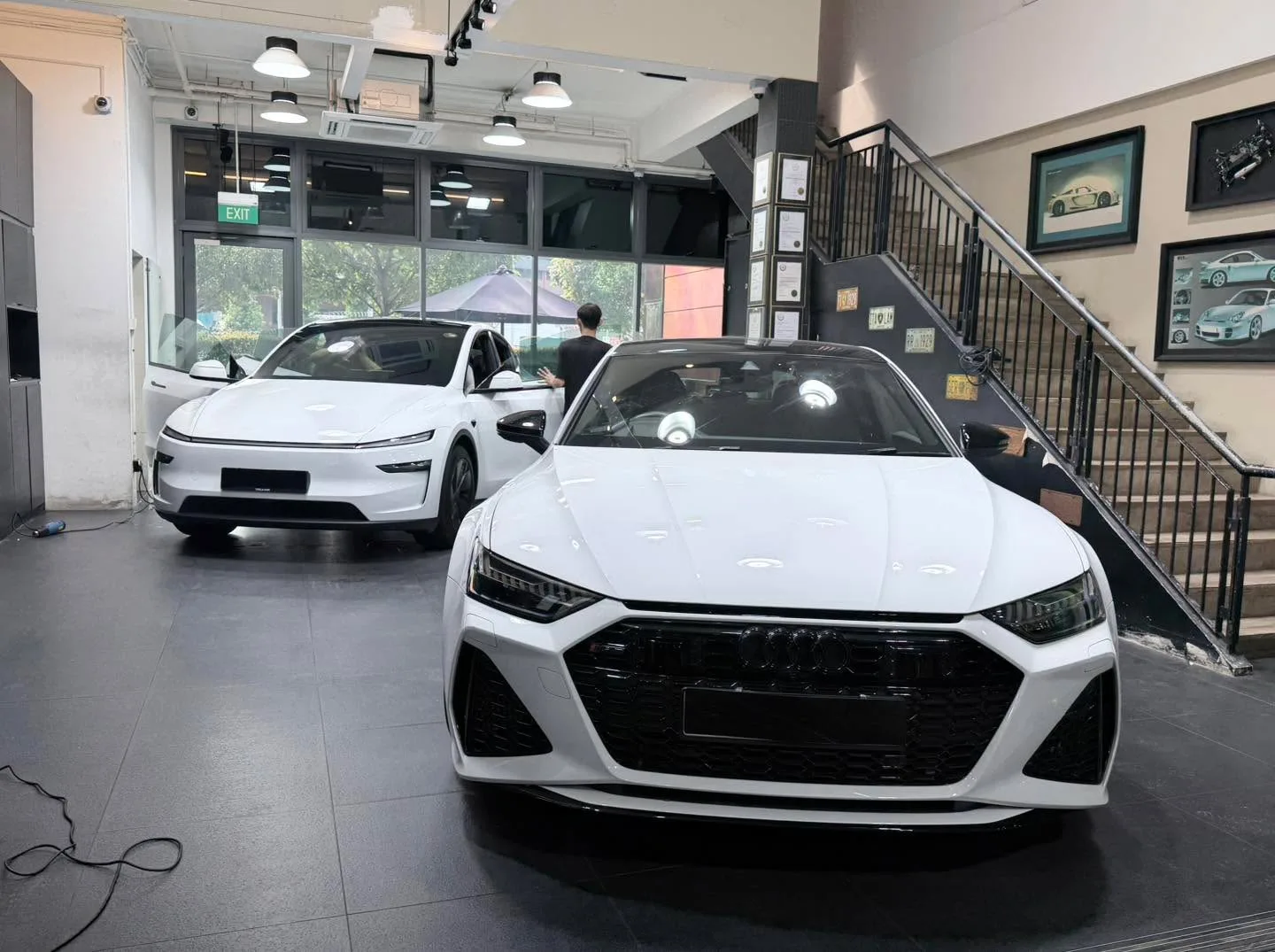 A white sedan with dark grille and white sedan inside a showroom.