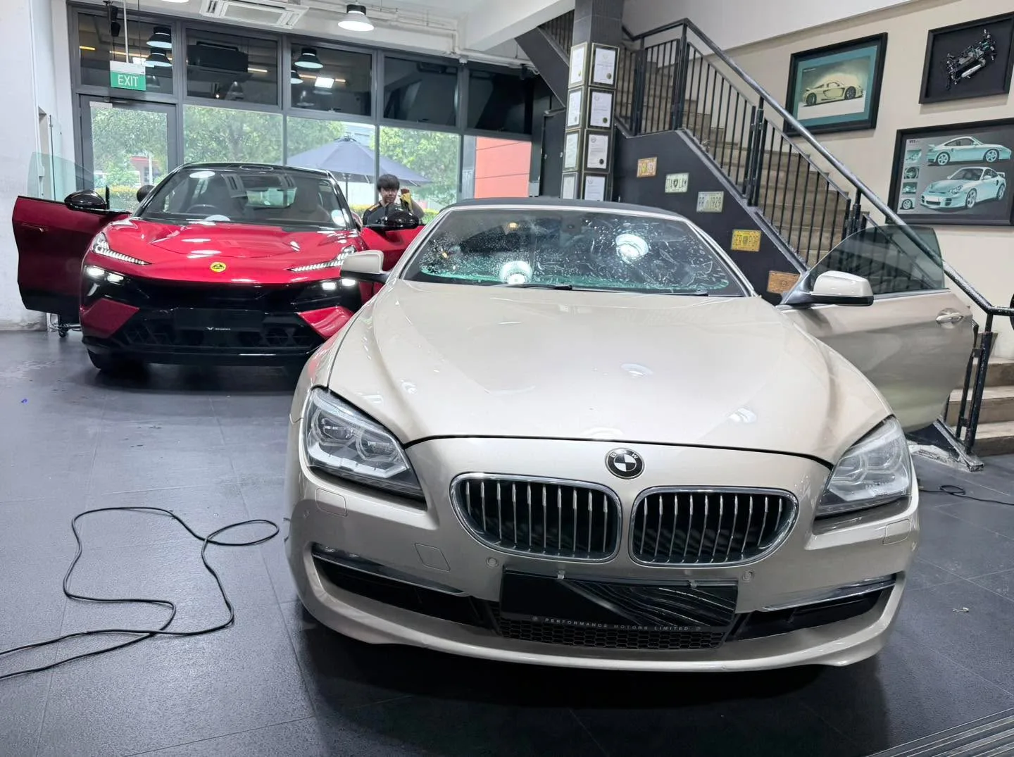 A white sedan with dark accents and red sports car in a showroom space.