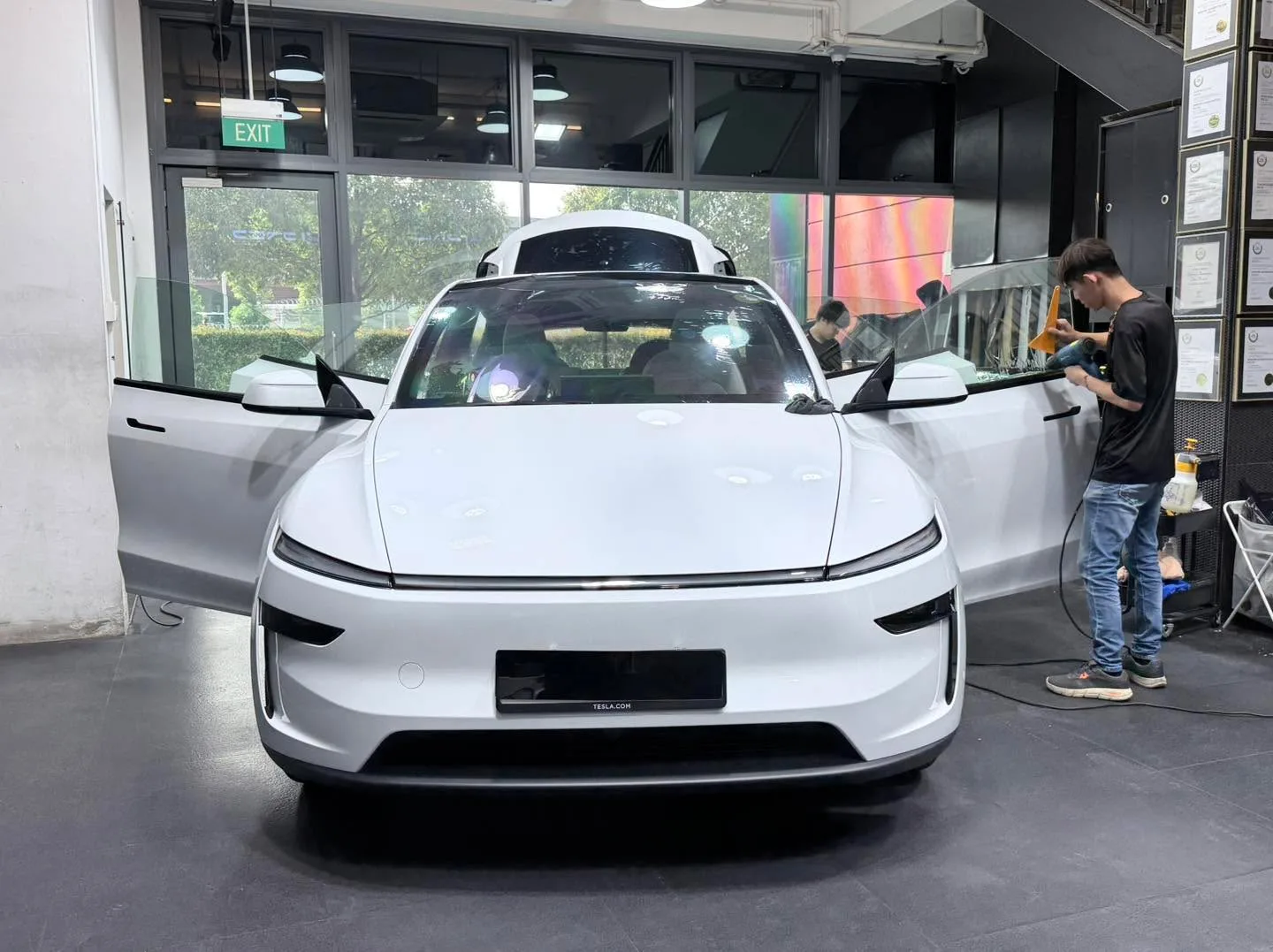 A white crossover with doors open, technician working on windows.