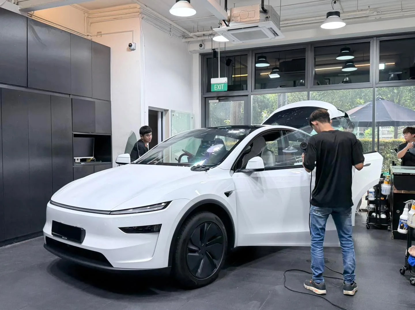 A white compact car inside the workshop with staff attending to it.