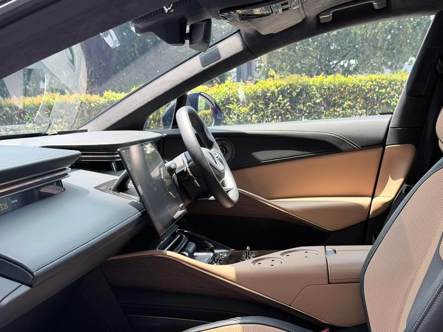 Interior view of a car showing a light brown leather dashboard, steering wheel, and display screen.