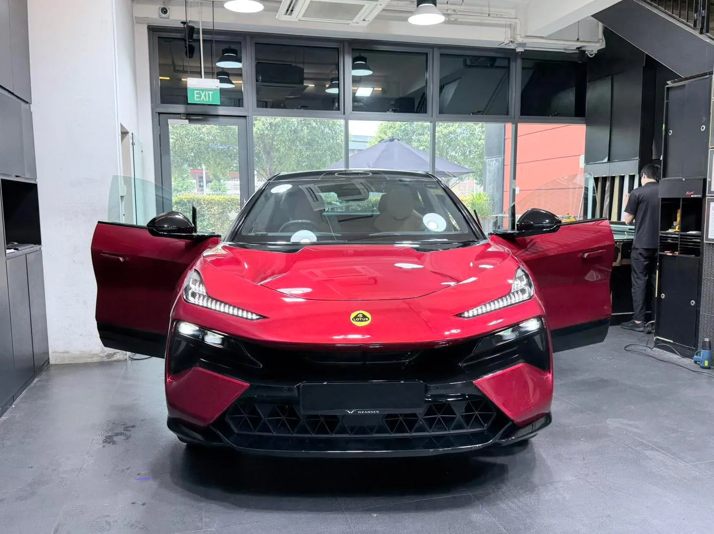 A red Lotus Eletre with doors open positioned inside the workshop facing forward.