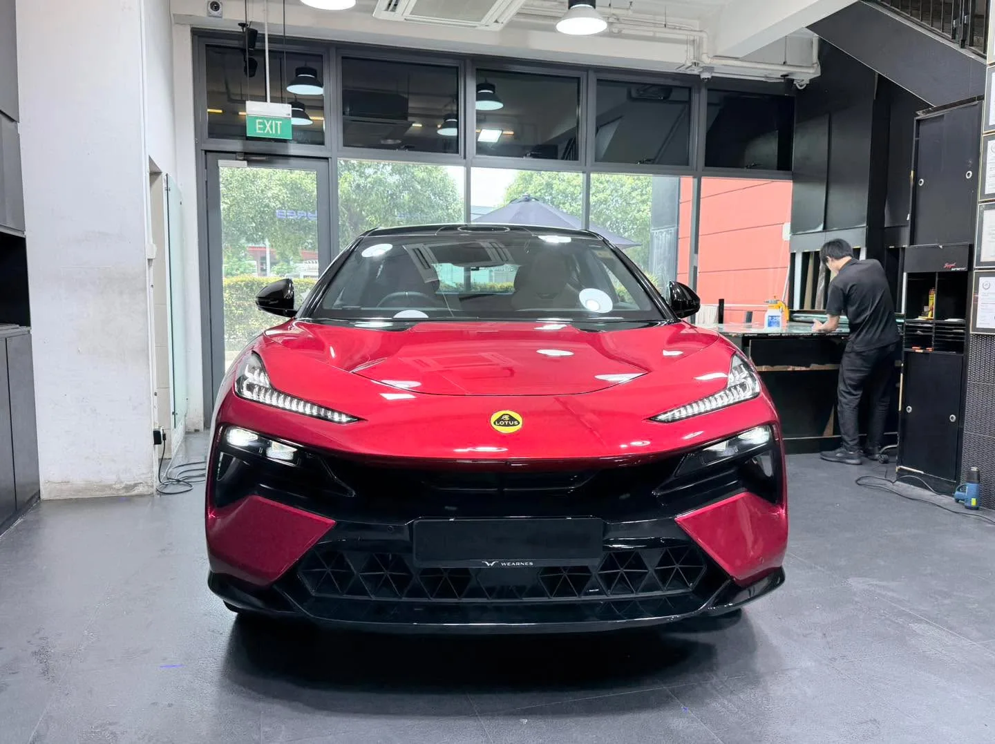 A red Lotus Eletre parked indoors at the workshop showing front-on view with doors closed.
