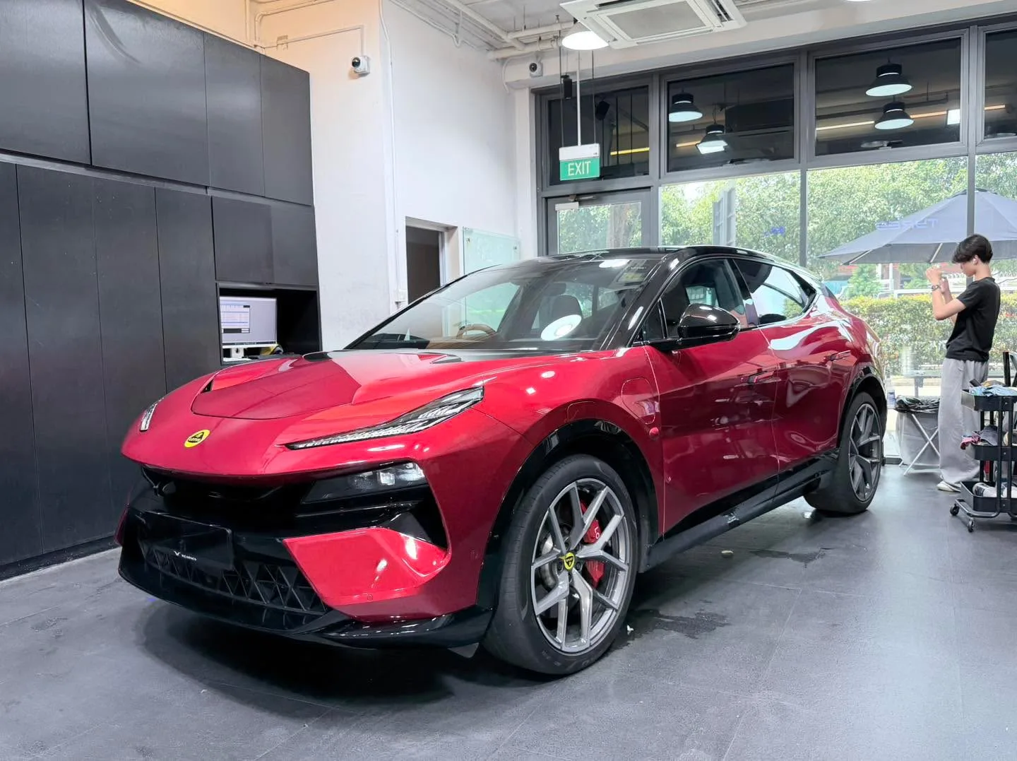 A red Lotus Eletre parked indoors with a technician visible to the right.