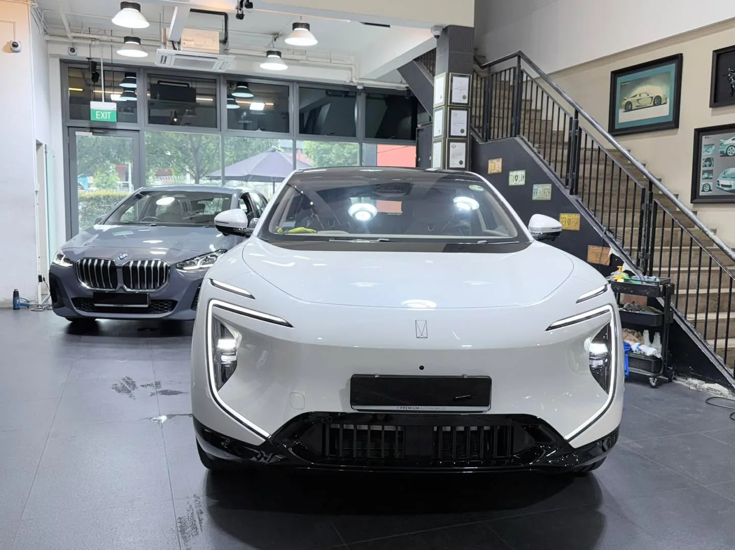 A white electric sedan and a dark blue BMW sedan parked indoors.
