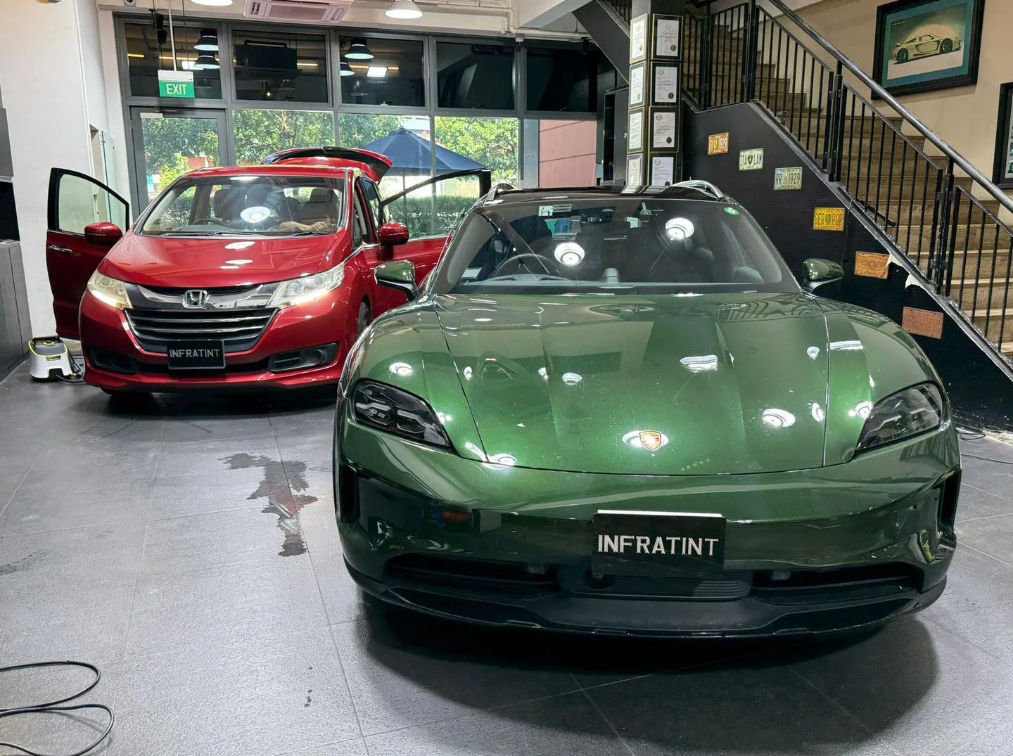 A green electric sports car and a red Honda minivan inside the workshop.