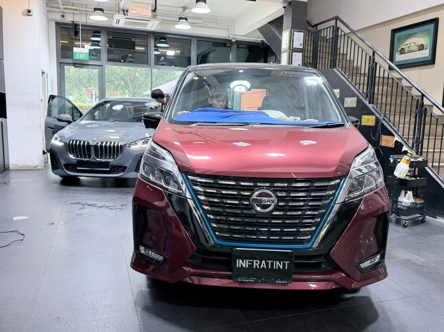 A burgundy Nissan Serena and a burgundy Honda Odyssey minivan in the workshop.