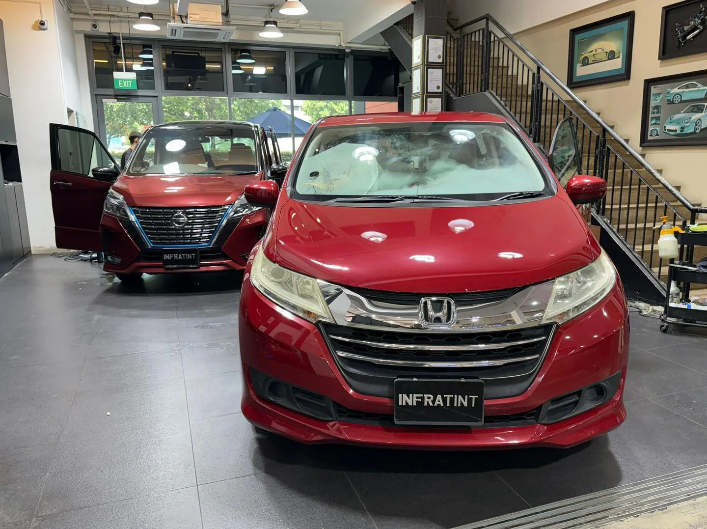 A burgundy Nissan Serena minivan with door open and a burgundy Honda minivan parked together.