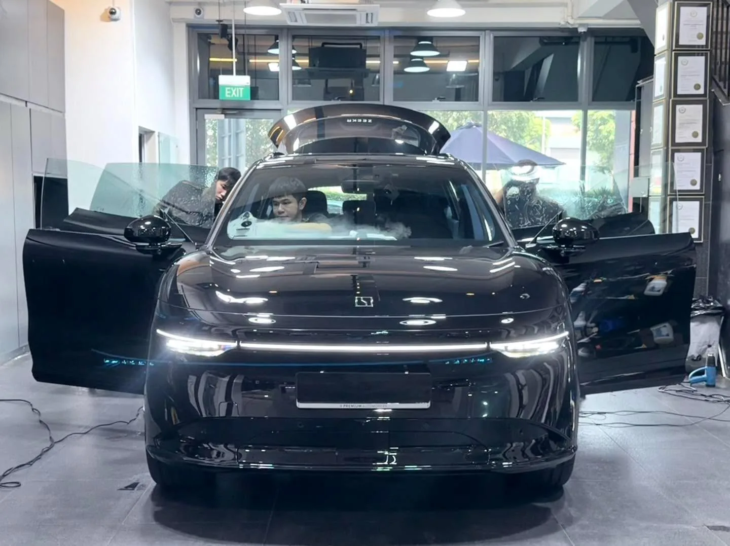 Black electric saloon with gull-wing doors open and a technician inside.