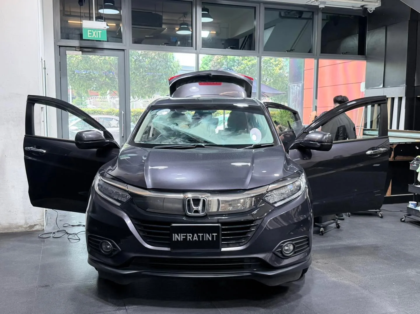 Black Honda Vezel compact SUV with doors open and a technician working.