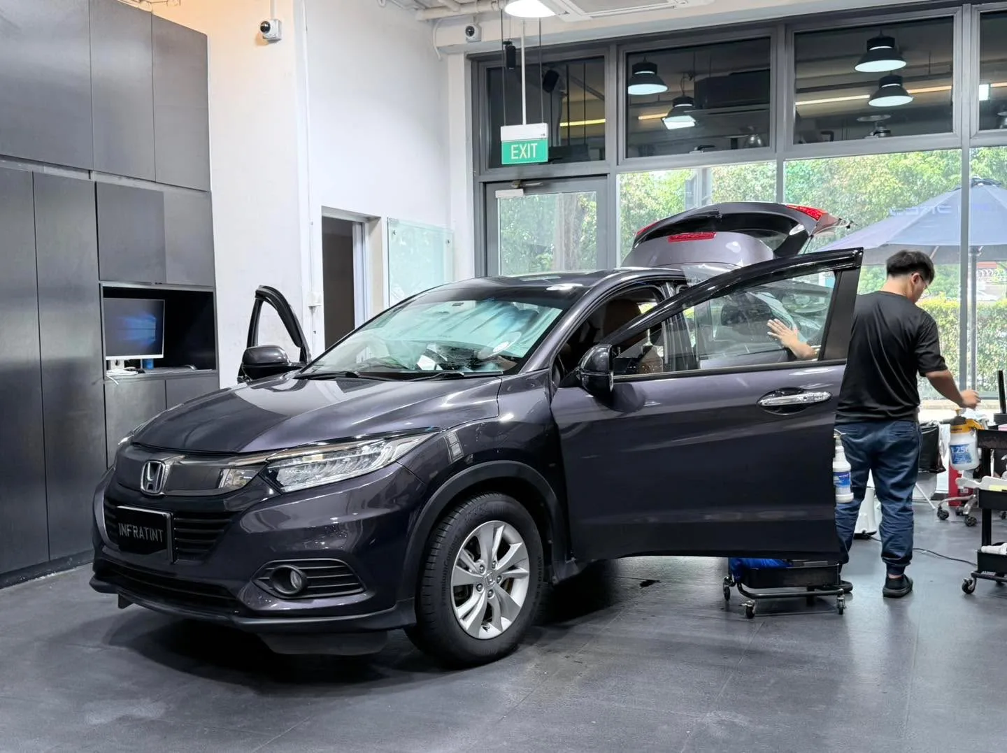 Grey Honda Vezel with a technician applying film.