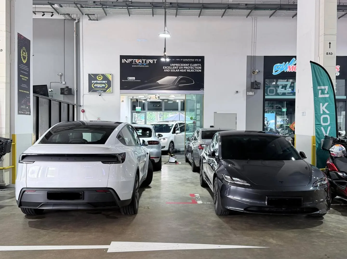 The same white Porsche SUV and dark Tesla sedan from a different angle.