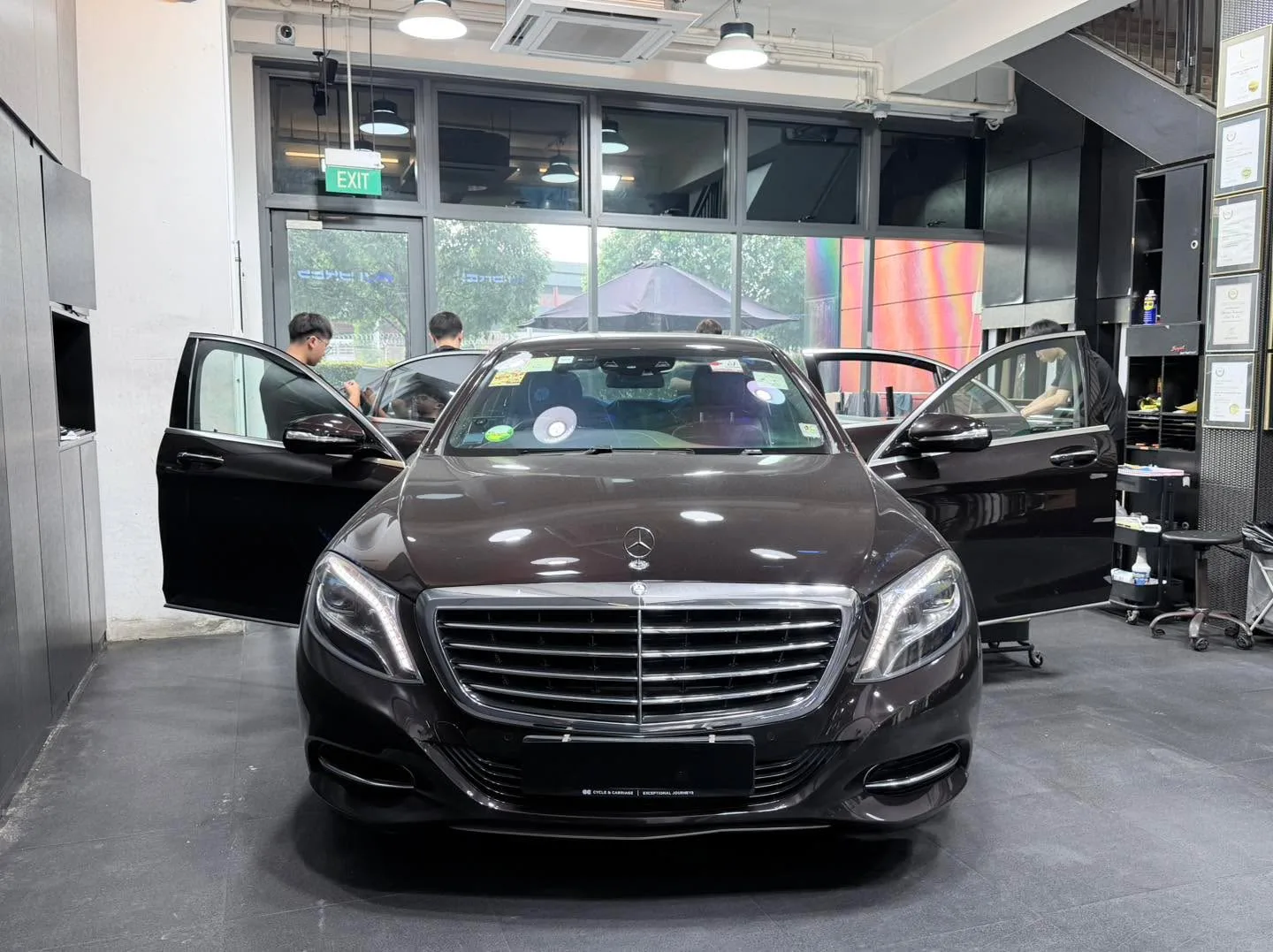 A black Mercedes-Benz sedan with doors open in the workshop.