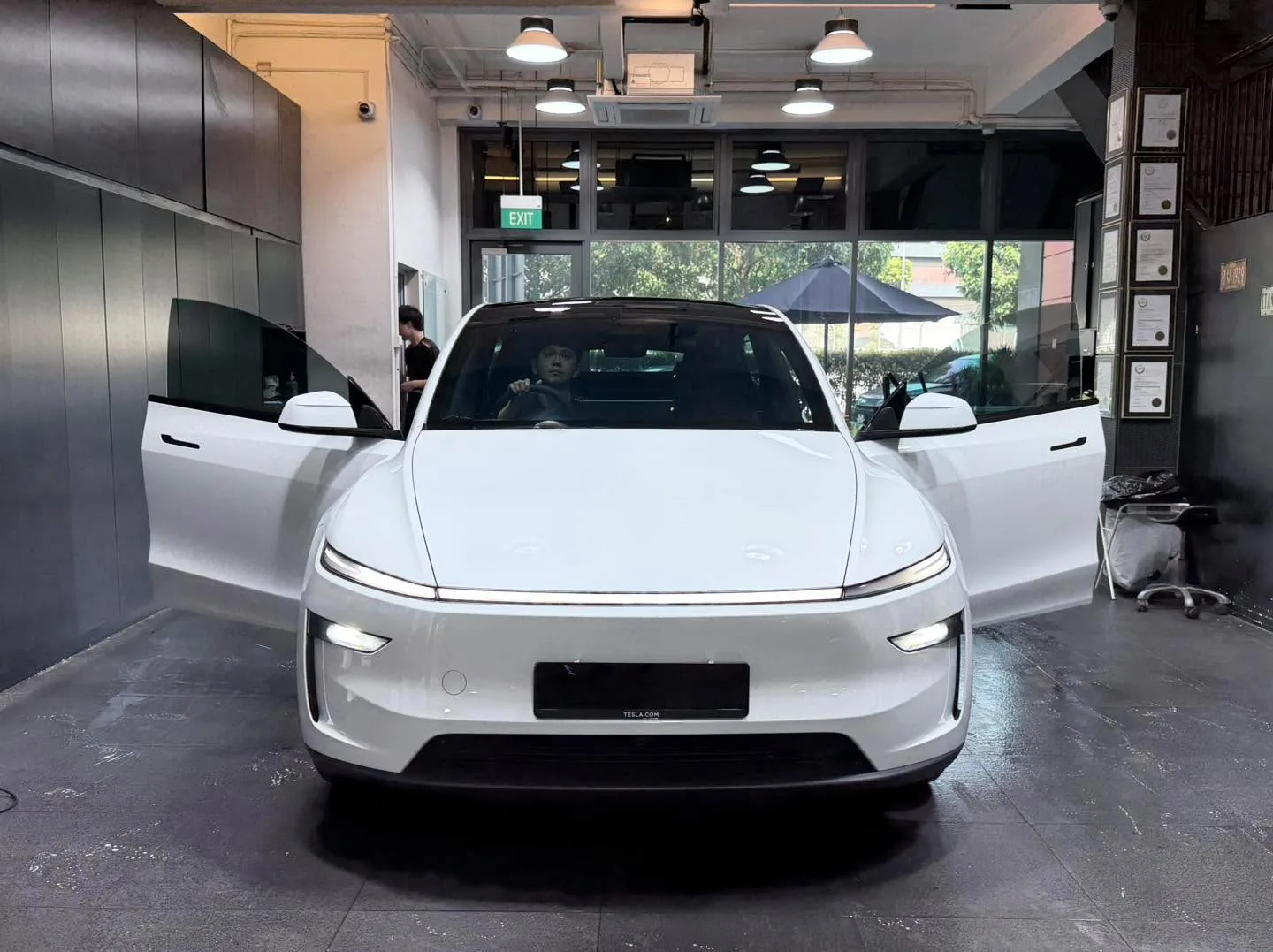 A white Tesla sedan with doors open in the workshop.