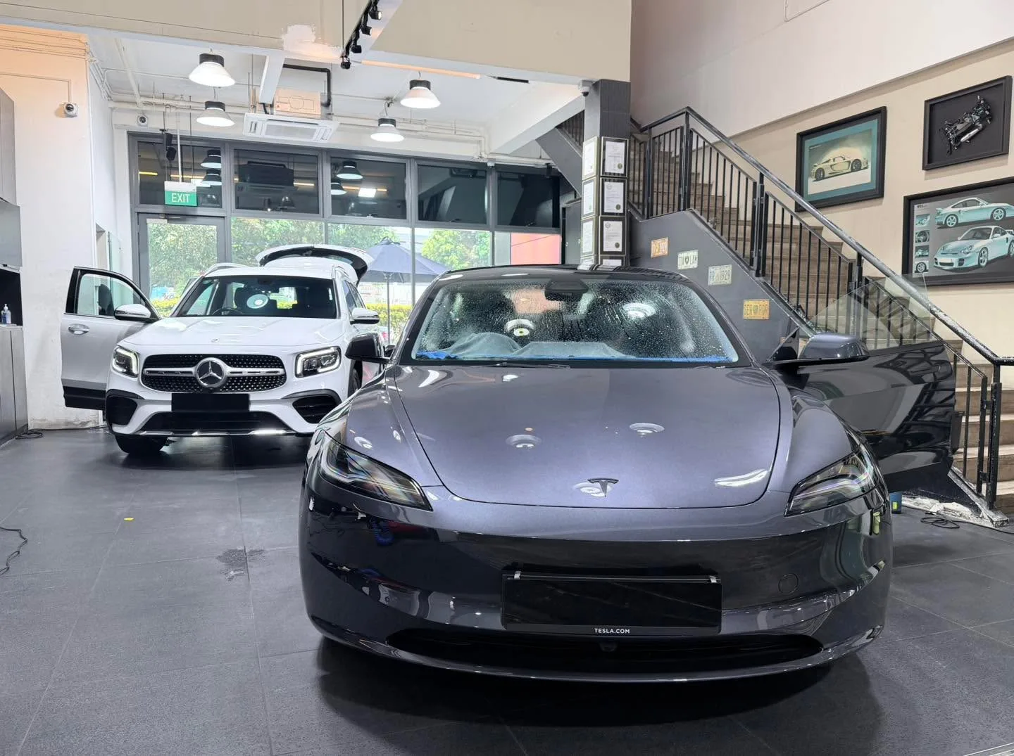 A dark Tesla sedan viewed from the front inside the workshop.