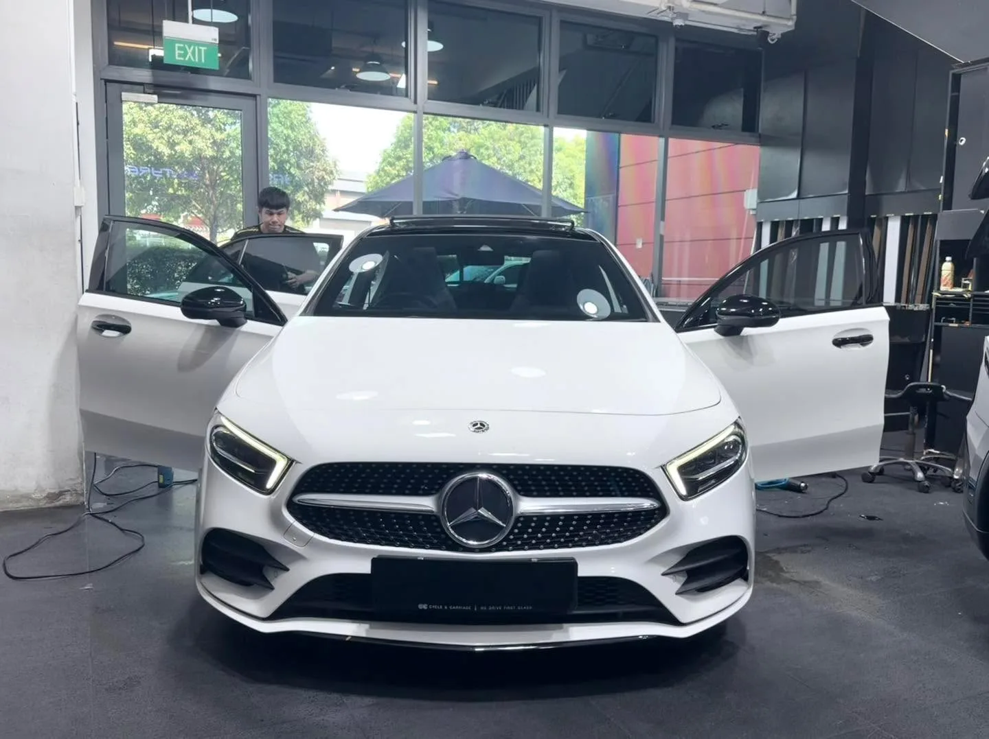 A white Mercedes-Benz GLA with doors open as technicians work on the windows.
