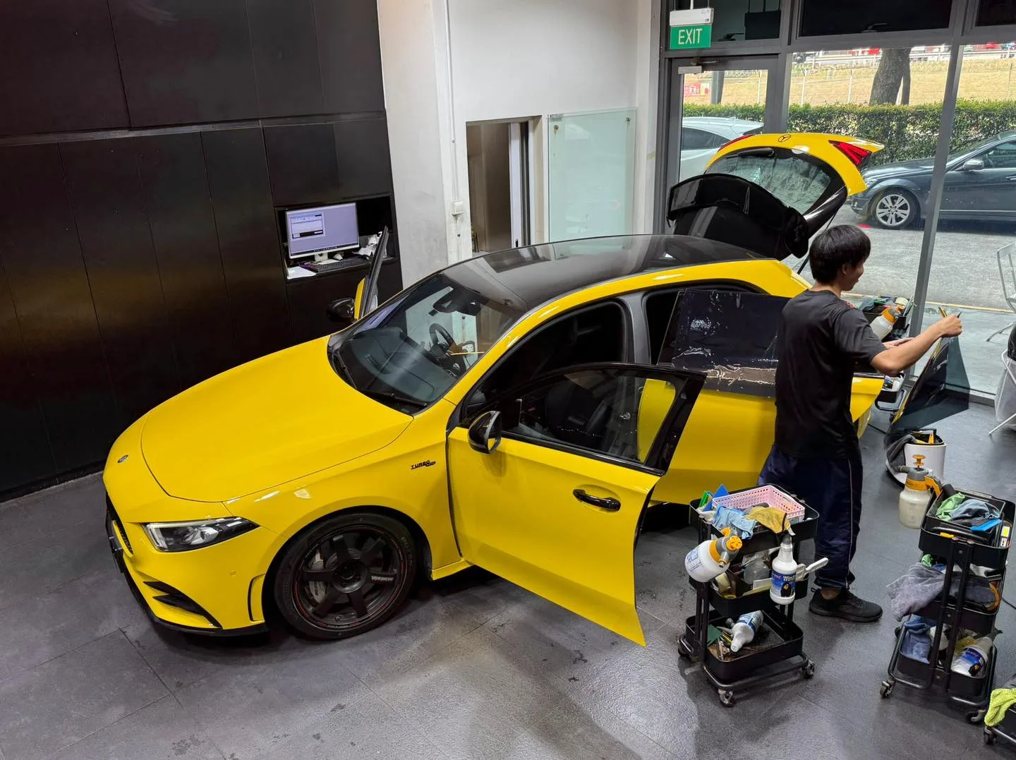 A dark blue electric SUV with its roof panel open, technicians working on the windows inside the workshop.