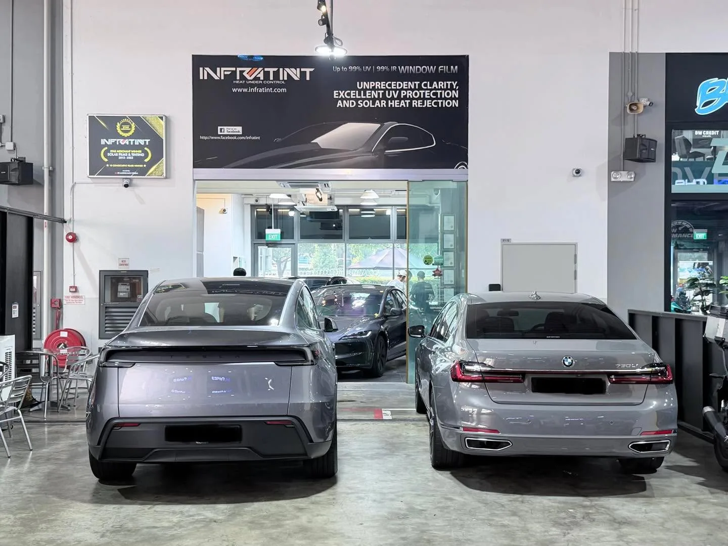 A silver sedan and a grey sedan parked side by side in the workshop.