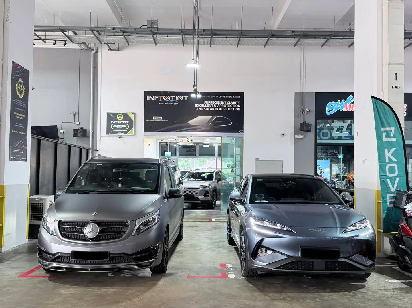 A silver minivan and a grey hatchback parked in the workshop.