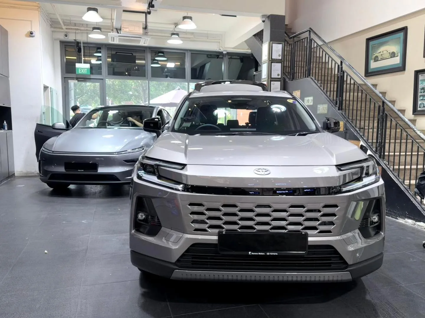 A grey SUV and a silver sedan parked indoors under LED lights.