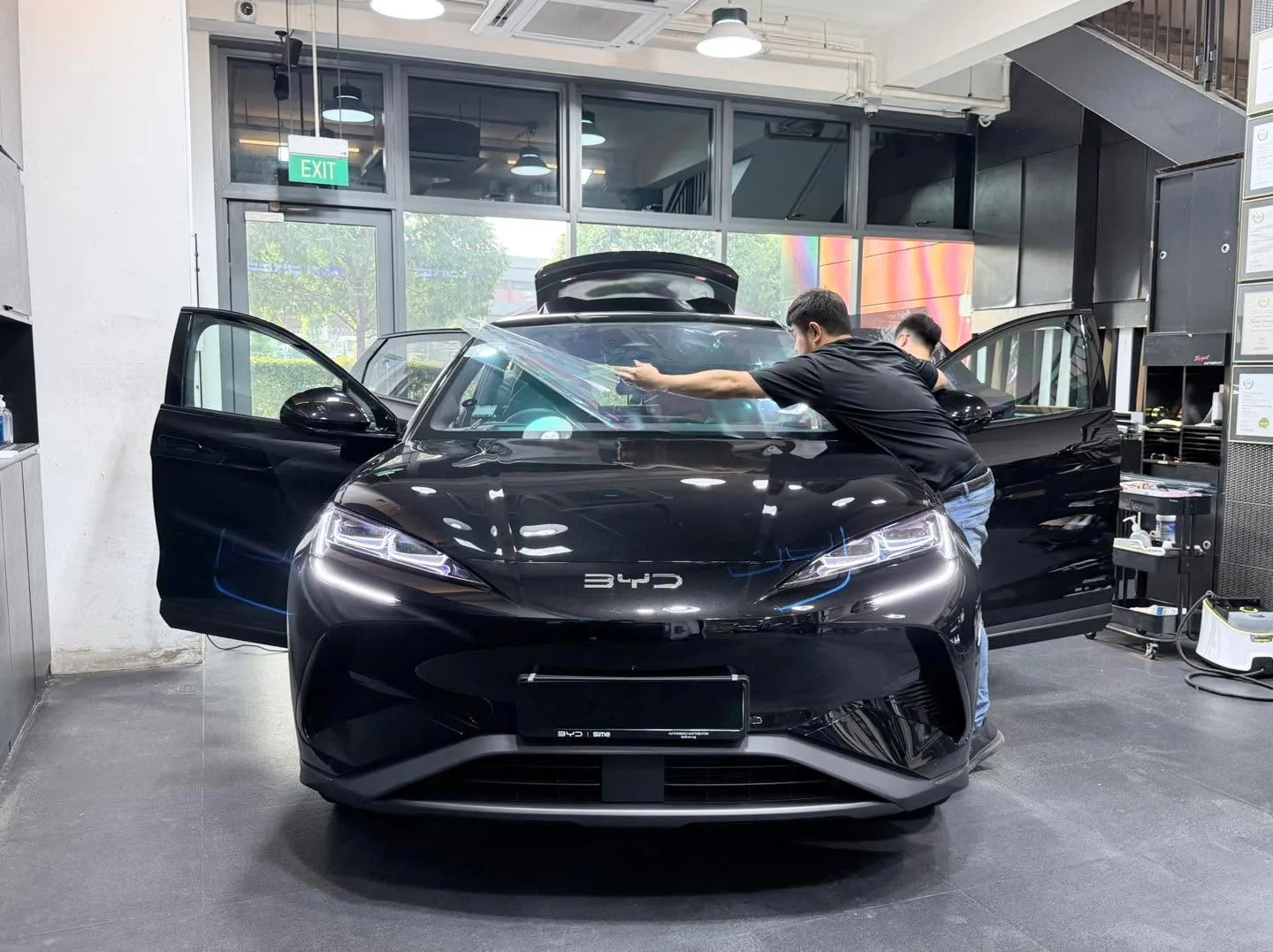 A black BYD Sealing hatchback with open door during tinting work.