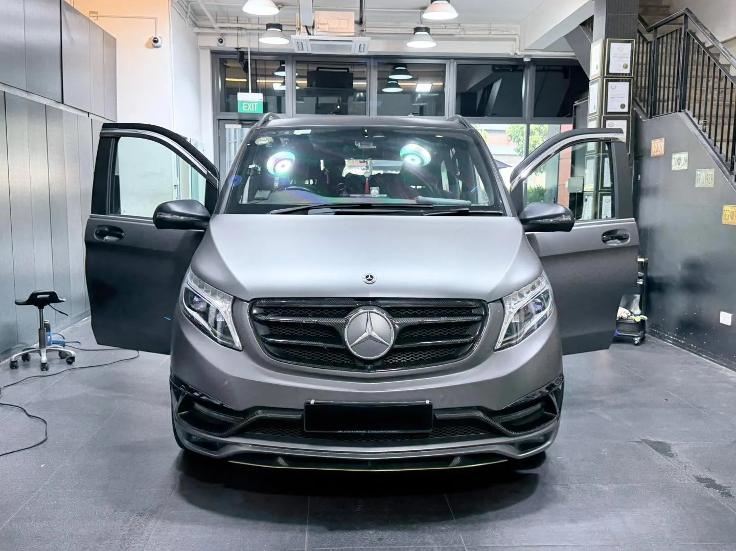 A silver Mercedes-Benz minivan with both side doors open during tinting work.