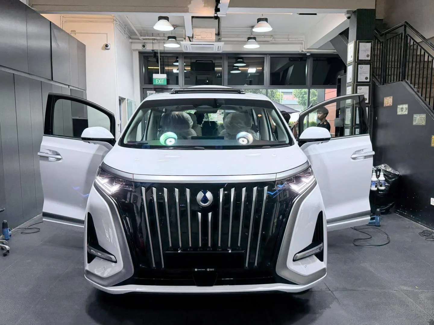 White Denza D9 SUV front view with doors open in workshop.
