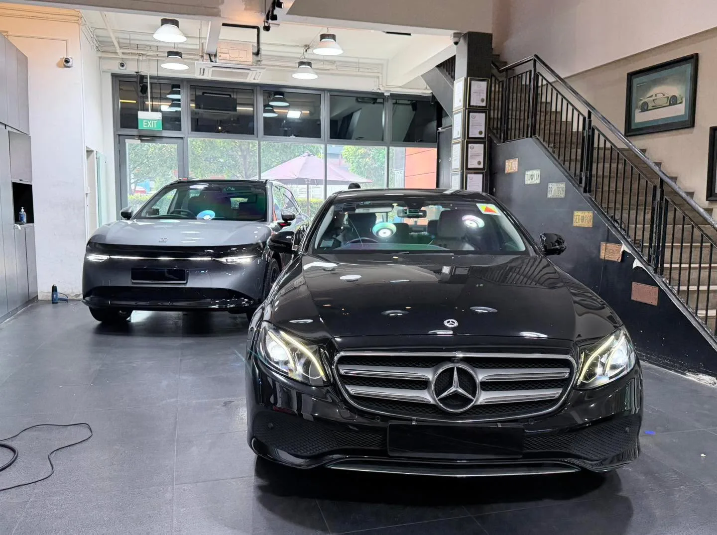 A black Mercedes-Benz sedan and a grey Zeekr SUV parked in the workshop.