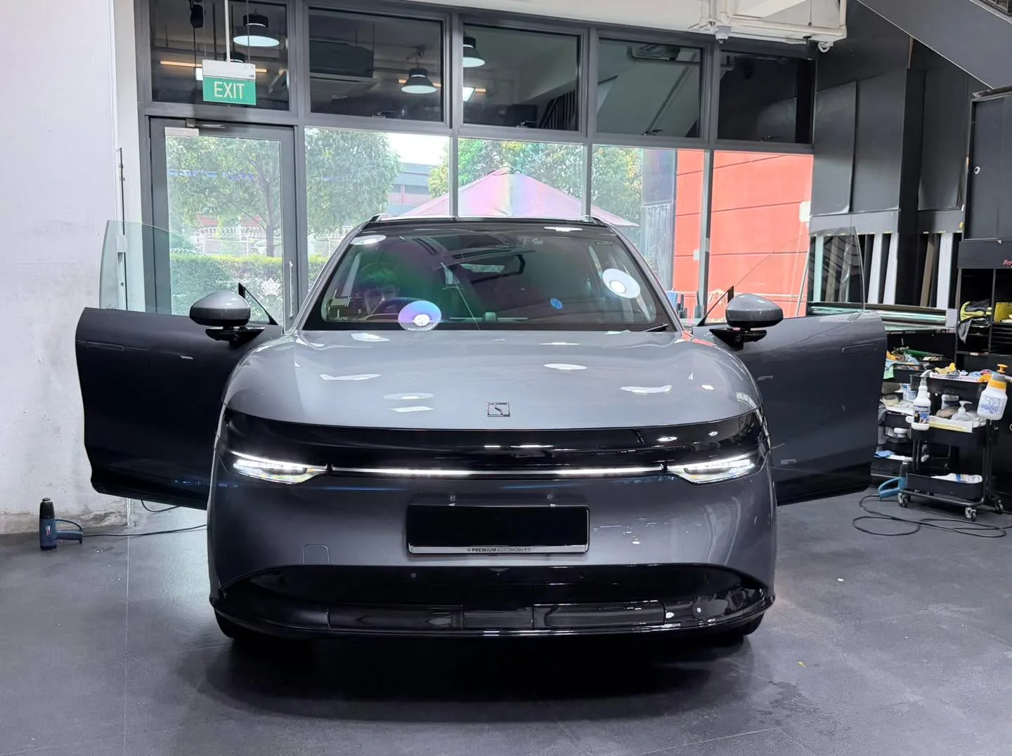 A dark grey Zeekr SUV with doors open in the workshop during tinting.