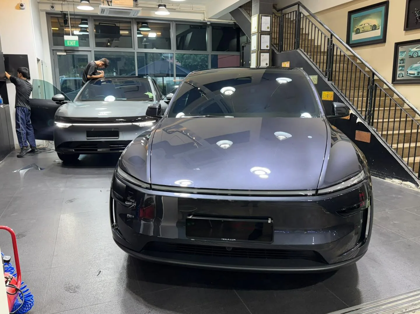 A grey electric SUV with angular headlights parked in the workshop, tinted windows visible.