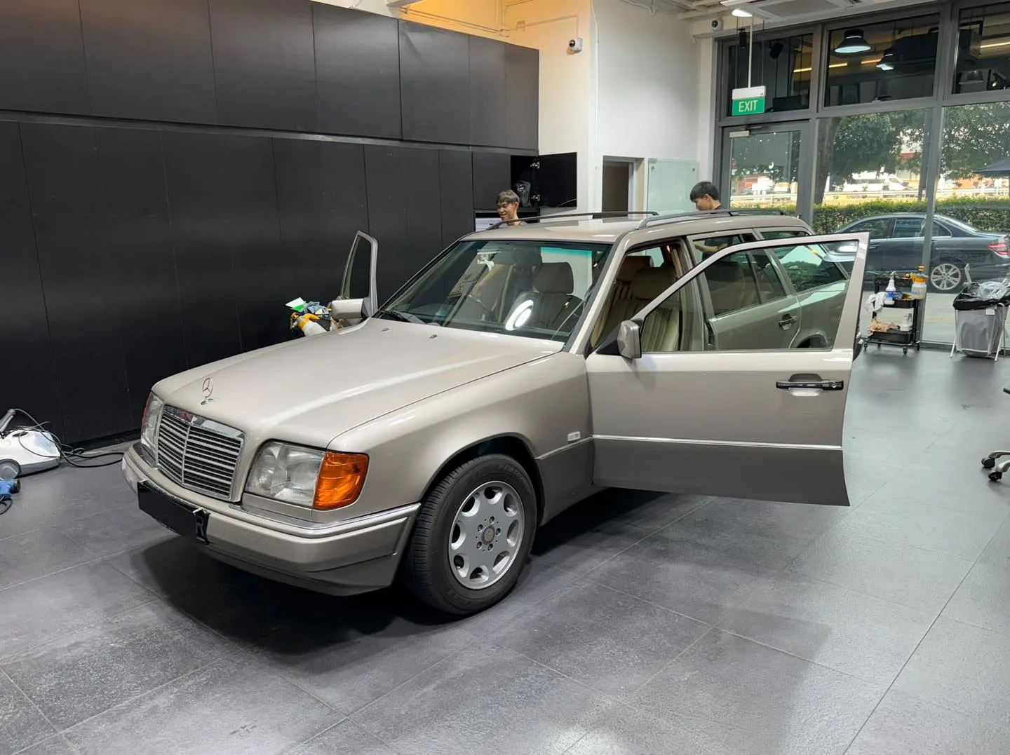 A white Mercedes-Benz W124 saloon with doors open, being prepared for tinting.