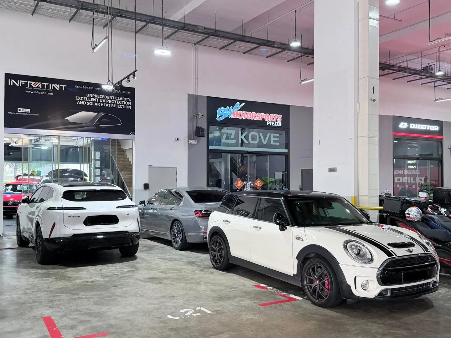 A white compact SUV, white hatchback, and white hatchback parked in a workshop at ground level.
