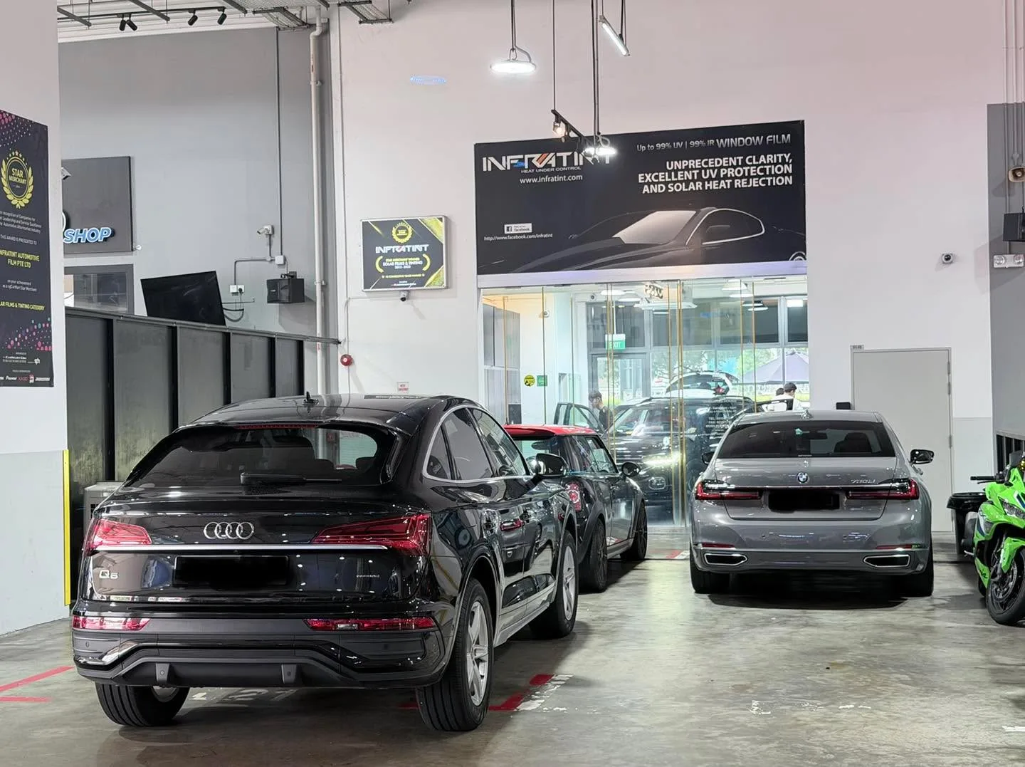A black Audi Q5 SUV parked indoors alongside a red Honda hatchback.