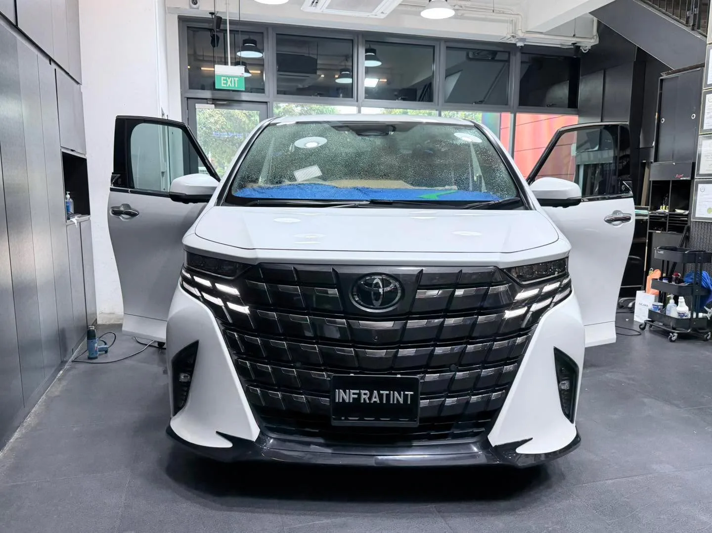 A white Toyota Alphard with doors open at the workshop.
