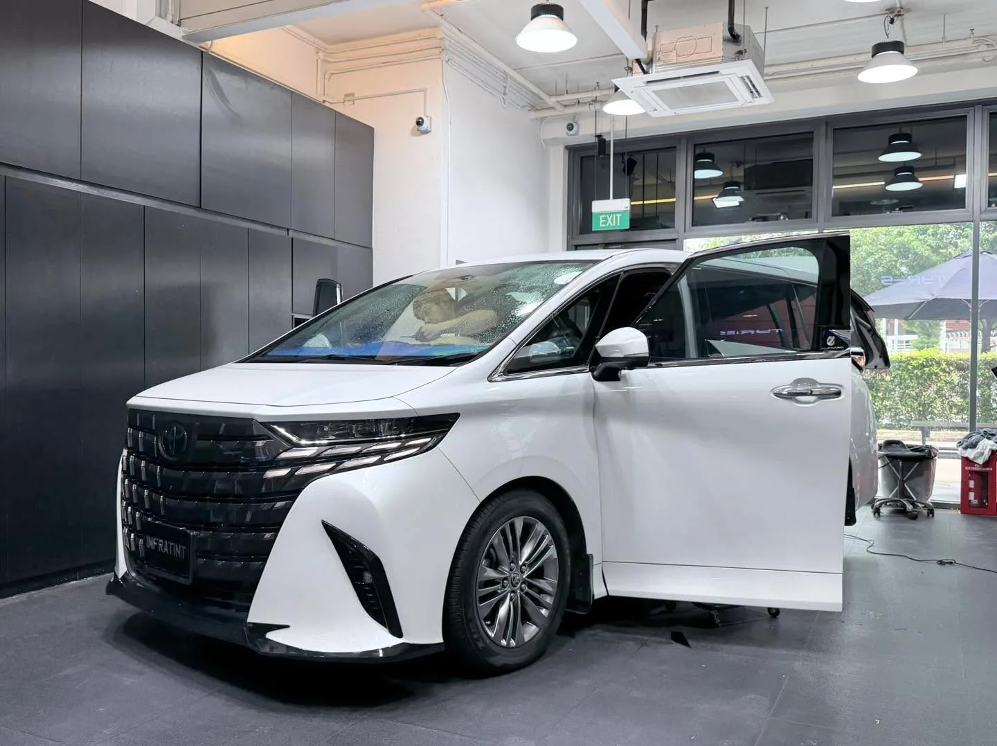 A white Toyota Alphard with the door open in the workshop.