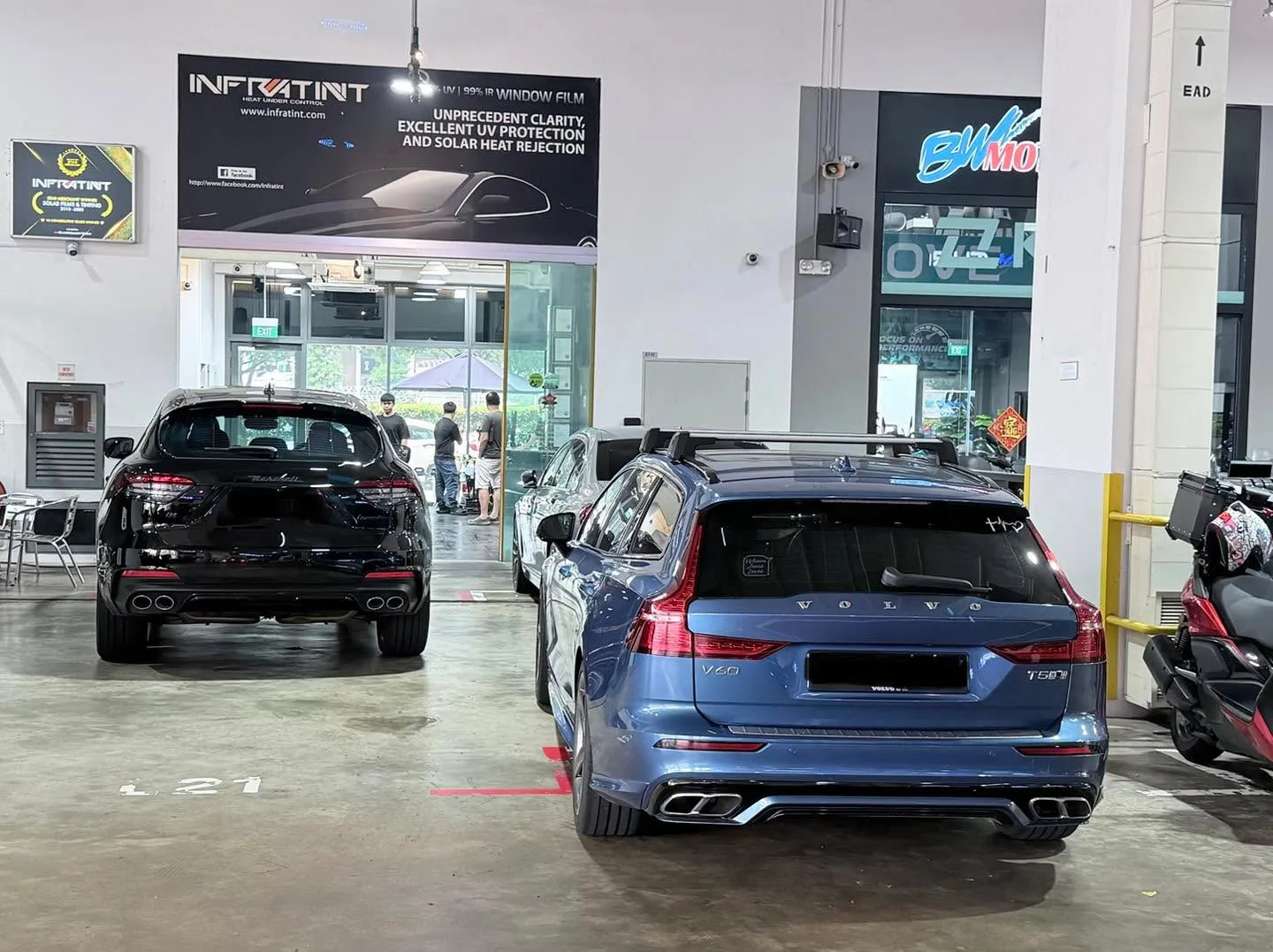 A black Maserati SUV and a blue Volvo estate parked in the workshop.